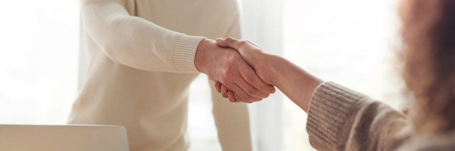 Close-up of professionals shaking hands over coffee in a modern office.